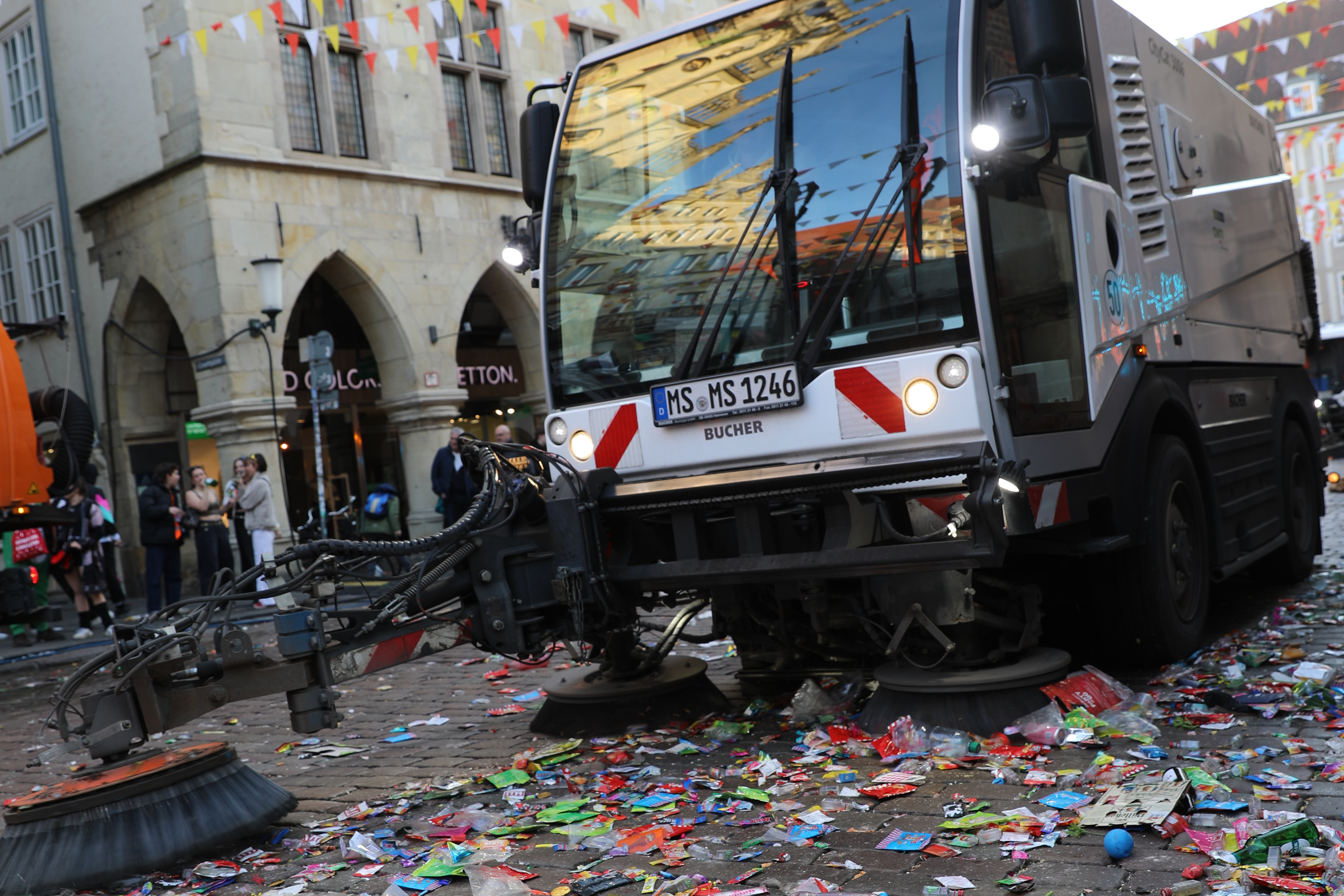 Abfall auf der Straße und ein Entsorgungsfahrzeug in Arbeit