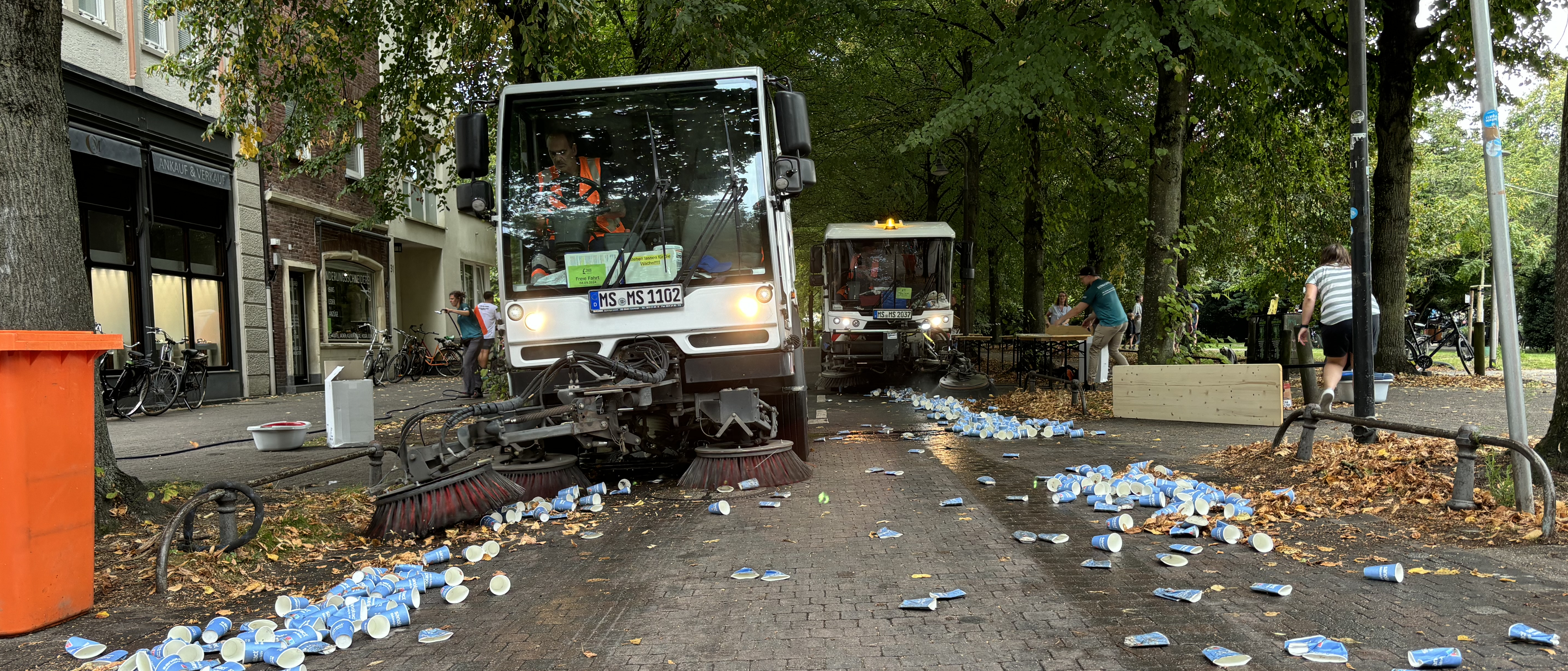 Ein Abfallfahrzeug auf der Promenade sammelt Becher