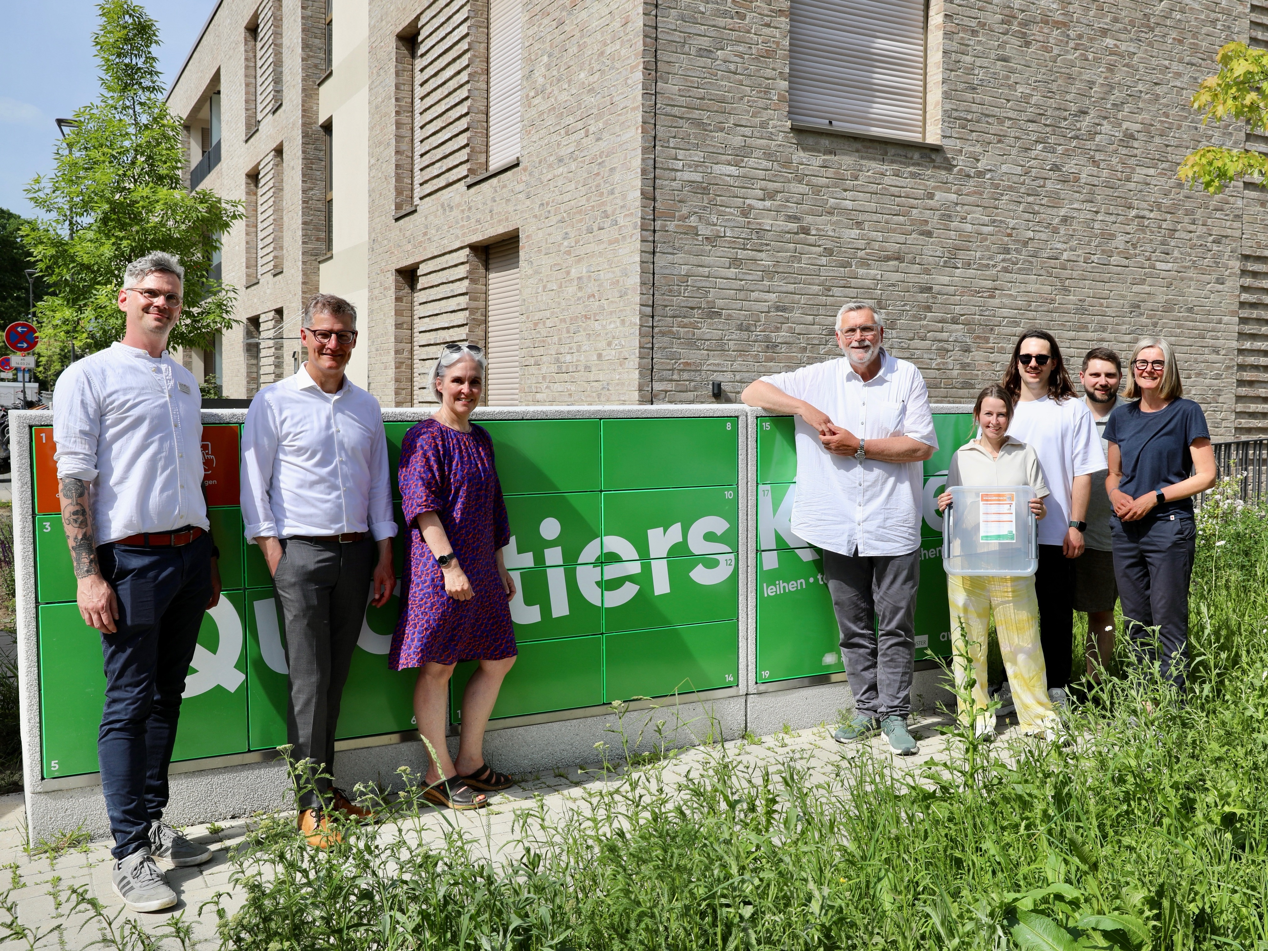 Foto von der Eröffnung der Quartierskiste im York-Quartier. Zu sehen sind: v. l.: Vinzenz Heidrich (Wohn + Stadtbau), Oberbürgermeister Tillmann Fuchs, Claudia Carl (KonvOY GmbH), Peter Bensmann (Bezirksbürgermeister Münster-Südost), Lena Recki, Lukas Böhm und Felix Peters (Reboot Mobility GmbH) sowie Stefanie Heeke (awm)