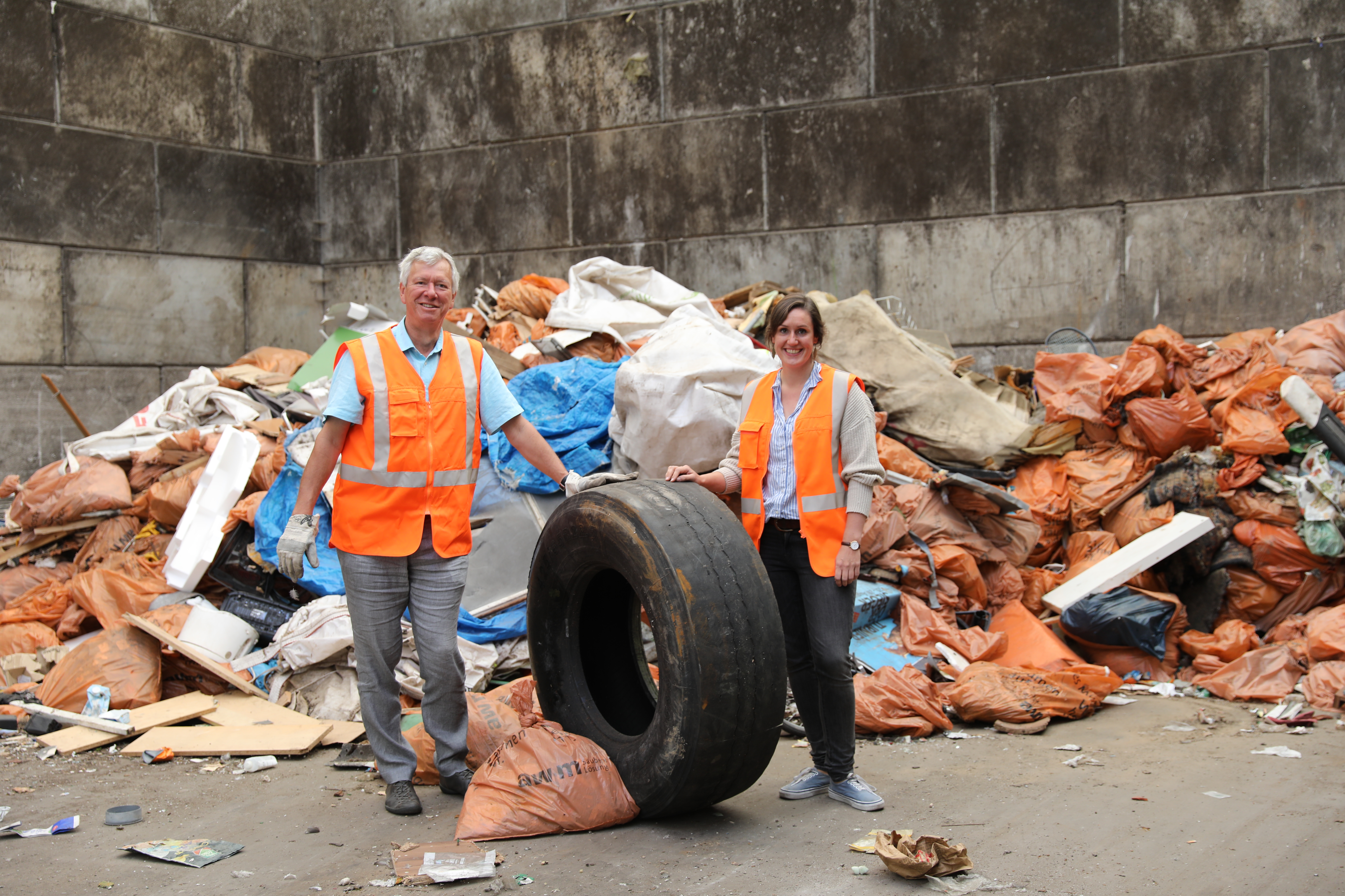 Hannah Lemli, Nachhaltigkeitspädagogin bei den awm und Patrick Hasenkamp, Betriebsleiter awm, inmitten des zusammengetragenen Abfalls.